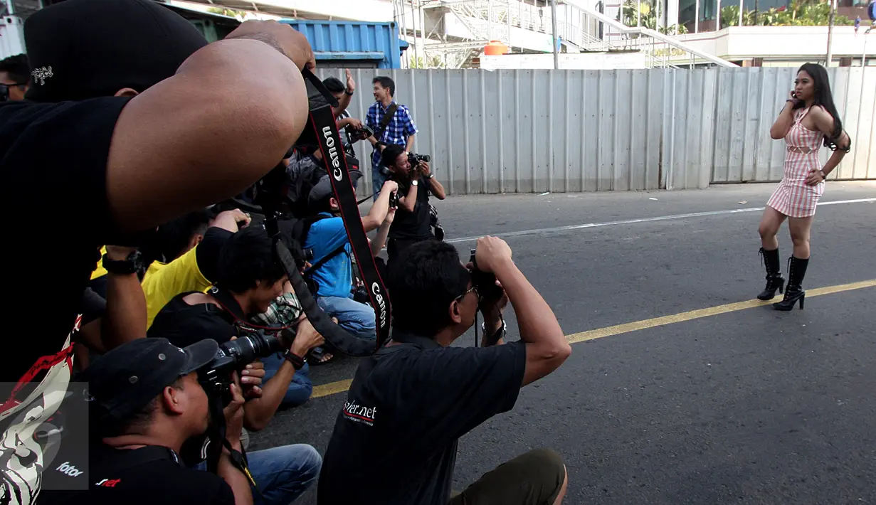 Sejumlah fotografer memotret seorang model yang berpose di Jalan MH Thamrin, Jakarta, Minggu (19/7/2015). Momen Jakarta sepi akibat banyak yang mudik, dimanfaatkan fotografer untuk memotret model. (Liputan6.com/Johan Tallo)