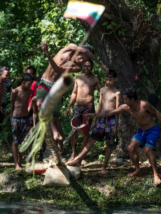 Seorang pria berjalan di atas tiang untuk mencoba meraih bendera nasional memperingati Hari Kemerdekaan Myanmar di pinggiran Yangon (4/1). Myanmar merayakan peringatan ke-71 deklarasi kemerdekaannya dari kolonial Inggris. (AFP Photo/Ye Aung Thu)