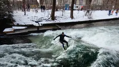 Seorang pria menaklukkan ombak saat berselancar di Sungai Eisbach selama hari musim dingin di Munich, Jerman, 4 Januari 2017. Eisbach merupakan sungai buatan dengan panjang dua kilometer dan arusnya pun merupakan buatan. (Mark RALSTON/AFP)