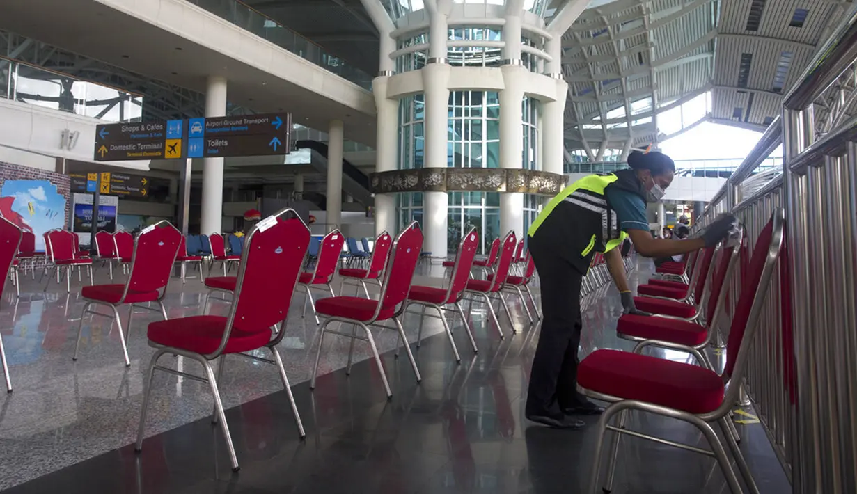 Seorang pekerja membersihkan kursi ruang tunggu Bandara Internasional Ngurah Rai di Bali, Sabtu (9/10/2021). Bandara Internasional Ngurah Rai akan kembali dibuka setelah ditutup lebih dari setahun karena pandemi COVID-19. (AP Photo/Firdia Lisnawati)