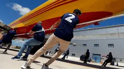 Anggota tim berusaha untuk menarik pesawat DHL Boeing 757 sejauh 20 meter di Safi Aviation Park, Malta pada 1 Mei 2019. Kegiatan tarik pesawat tersebut merupakan rangkaian dalam rangka untuk penggalangan dana amal. (REUTERS/Darrin Zammit Lupi)