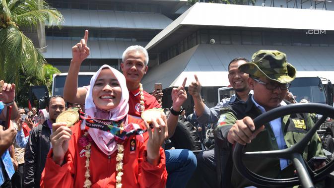 Peraih 2 medali emas dari cabor panjat tebing, Aries Susanti Rahayu menunjukkan medali saat hendak diarak keliling Kota Semarang, Selasa (4/9). Sejumlah atlet asal Jawa Tengah yang meraih medali Asian Games diarak keliling Semarang. (Liputan6.com/Gholib)