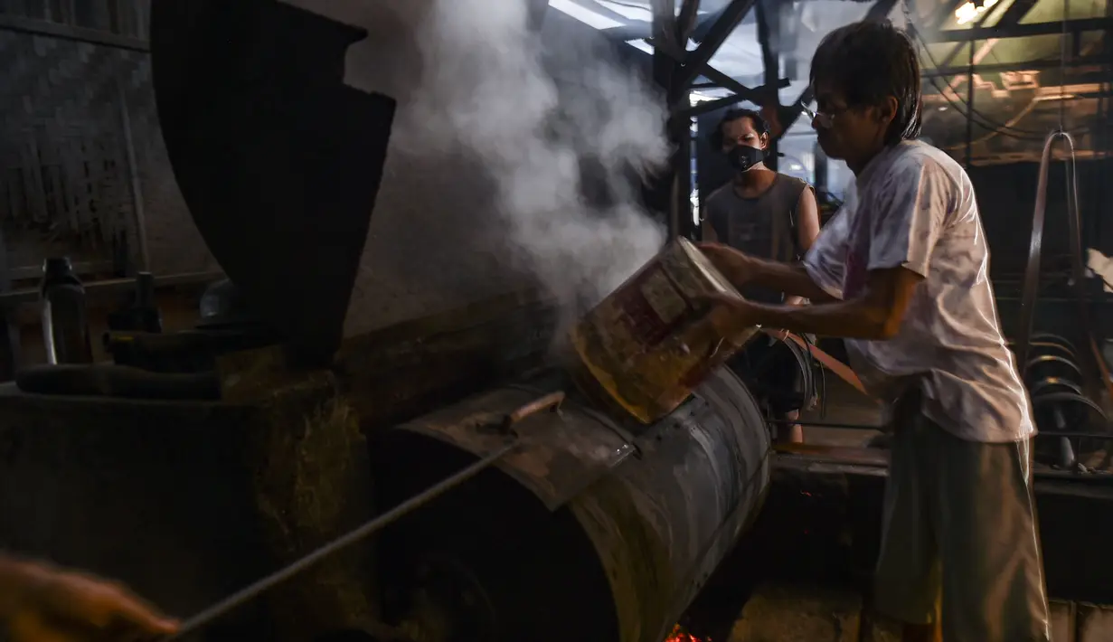 Pekerja memanggang biji kopi robusta dengan cara tradisional di sebuah produsen biji kopi kecil di Banda Aceh (14/11/2020). (AFP/Chaideer Mahyuddin)