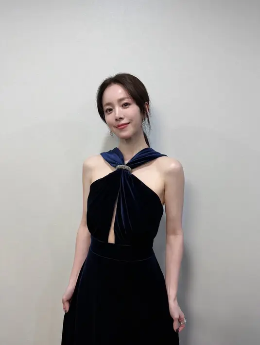 <p>Han Ji Min tampil elegan mengenakan long dress navy berbahan velvet model cross neck. Melengkapi tampilannya anting-anting silver. Rambut panjang diikat ke belakang.&nbsp;[@bhent_official]</p>