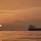 Matahari terbit di balik kapal tanker yang berlabuh di Selat Hormuz di lepas pantai Pulau Qeshm, Iran, Sabtu, 18 April 2026. (AP Photo/Asghar Besharati)