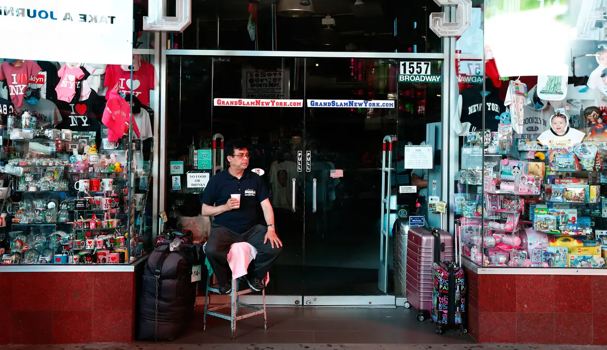 Seorang pemilik toko duduk di luar tokonya selama pemadaman listrik di Times Square, New York, AS, Sabtu (13/7/2019).  Pemadaman listrik juga mempengaruhi bagian barat Manhattan, khususnya kawasan Hell's Kitchen dan teater Broadway. (AP Photo/Michael Owens)