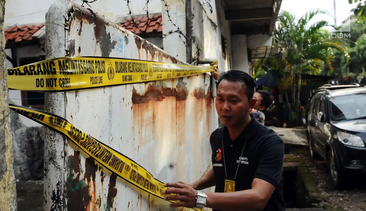 Petugas memasang garis polisi usai menggeledah rumah tersangka penampung TKI Ilegal di Jalan Percetakan Negara X, Jakarta, Rabu (31/5). Bersama satu tersangka, petugas Dirtipidum Mabes Polri mencari barang bukti baru. (Liputan6.com/Helmi Fithriansyah)