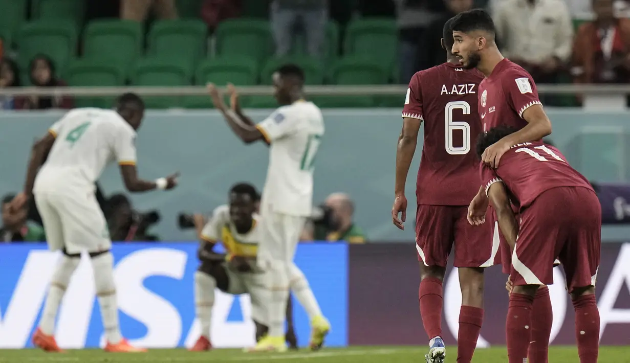 <p>Pemain Senegal di latar belakang merayakan kemenangan 3-1 mereka saat pemain Qatar menunjukkan kekecewaan mereka, setelah pertandingan sepak bola grup A Piala Dunia antara Qatar dan Senegal, di Stadion Al Thumama di Doha, Qatar, Jumat, 25 November 2022. (AP Photo/Ariel Schalit)</p>