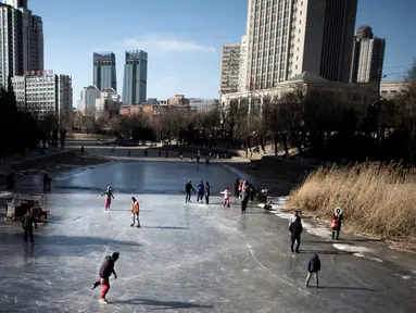 Sejumlah warga bermain ice skating di sungai yang membeku di Beijing, China (21/1). Akibat membeku, Sungai ini menjadi objek wisata dadakan yang banyak diminati wisatawan. (AFP/Fred Dufour)