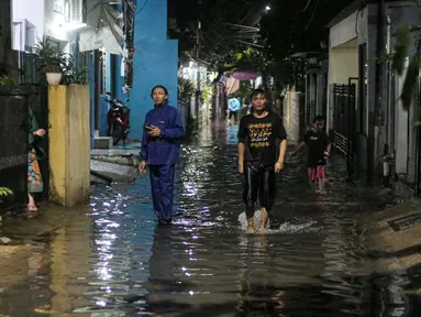 Warga berjalan menerjang banjir karena hujan di Jalan Shofa Marwah, Jakarta, Jumat (4/11/2022). Berdasarkan laporan Badan Penanggulangan Bencana Daerah (BPBD) DKI Jakarta yang diperbaharui pada pukul 18.00 WIB, terdapat 4 RT yang terendam banjir dengan ketinggian maksimal mencapai 50 Cm. (Liputan6.com/Faizal Fanani)