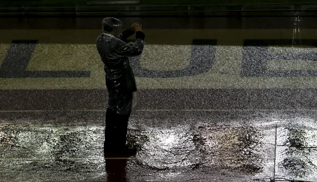 Seorang mengabadikan gambar dipinggir lapangan yang banjir akibat hujan lebat di stadion Monumental, Argentina, Jumat (13/11/2015). Karena cuaca buruk Pertandingan antara Argentina dan Brasil mengalami pengunduran. (REUTERS/Marcos Brindicci)
