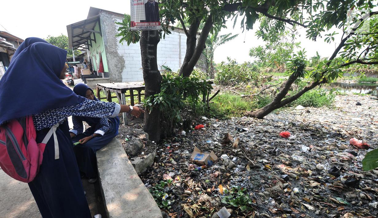 Anak sekolah melihat Kali Pisang Batu yang dipenuhi sampah, Tarumajaya, Bekasi, Jawa Barat, Rabu (9/1). Warga tetap beraktivitas sehari-hari meski bau tak sedap menghantui mereka akibat tumpukan sampah di Kali Pisang Batu. (Merdeka.com/Iqbal S. Nugroho)