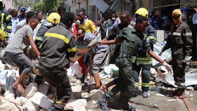 Petugas membawa jenazah korban di lokasi serangan bom mobil di Distrik Hamarwayne, Mogadishu, Ibu Kota Somalia (4/2). Setidaknya sembilan orang tewas dan beberapa lainnya cedera akibat serangan bom mobil tersebut. (AFP Photo/Abdirazak Hussein Farah)