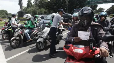 Petugas Dishub DKI Jakarta melakukan sosialisasi lajur khusus sepeda motor di Jalan MH Thamrin, Jakarta, Senin (29/1). (Liputan6.com/Arya Manggala)