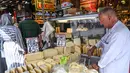 Seorang pedagang memotong keju di Spice Bazaar yang bersejarah di distrik Eminonu di Istanbul, Turki (13/7/2019). Spice Bazaar dipenuhi oleh pengunjung selama bulan ramadan. (AFP Photo/Ozam Kose)