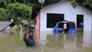 Seorang warga melambaikan tangan di dekat rumahnya yang dilanda banjir, Sri Lanka, Minggu (28/5). Atas bencana banjir dan longsor ini, Kementerian Luar Negeri Sri Lanka telah mengajukan permintaan bantuan dari PBB dan negara-negara tetangga. (AP Photo)
