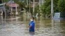 Seorang pria mengarungi jalan yang banjir di Hulu Langat, di luar Kuala Lumpur, Malaysia, Minggu (19/12/2021). Kuala Lumpur dan perkampungan sekitarnya dilanda banjir akibat hujan deras selama dua hari, menyebabkan ribuan warga mengungsi dan banyak jalan yang memutus akses. (AP Photo/Vincent Thian)