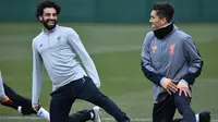 Penyerang Liverpool, Mohamed Salah (kiri) dan Roberto Firmino melakukan pemanasan saat latihan di Melwood Training Ground, Liverpool, Inggris (5/3). Liverpool akan melawan Porto pada leg kedua babak 16 besar Liga Champions. (AFP Photo/Anthony Devlin)