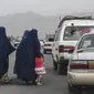Wanita mengenakan burqa menyeberang jalan saat mereka berjalan menuju taksi di Kabul, Afghanistan, 31 Juli 2021. (SAJAD HUSSAIN/AFP)