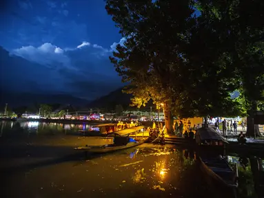 Orang-orang Kashmir duduk di tepi danau Dal pada malam hari di Srinagar, Kashmir yang dikuasai India, Minggu (1/8/2021). Danau terbesar kedua di propinsi Jammu dan Kashmir ini merupakan pusat pariwisata dan rekreasi. (AP Photo/Mukhtar Khan)