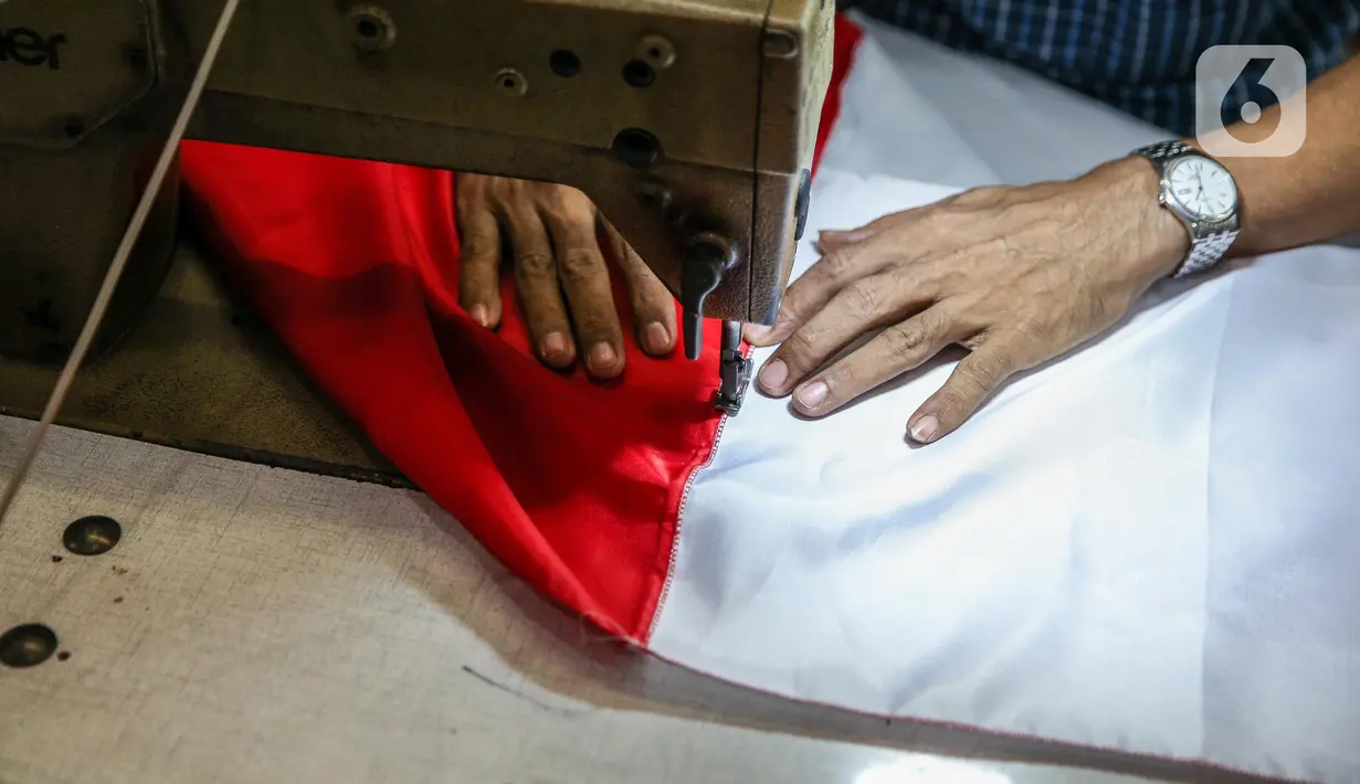 Pekerja menjahit bendera merah putih di kiosnya, kawasan Pasar Senen, Jakarta, Rabu (5/8/2020). Menjelang peringatan HUT ke-75 Kemerdekaan RI, sejumlah pedagang mengaku penjualan pernak-pernik bendera merah putih menurun 50 persen dibanding tahun lalu akibat COVID-19. (Liputan6.com/Faizal Fanani)