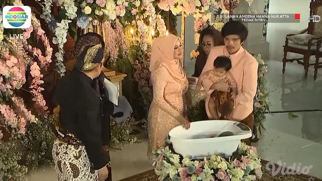 Atta Halilintar dan Aurel Hermansyah mendampingi putri mereka Ameena Hanna Nur Atta menjalani upacara Tedak Siten di acara 7 bulanan. (Foto: Indosiar/Vidio)