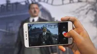 Pengunjung menggunakan ponsel untuk mengambil foto lilin Adolf Hitler berlatar belakang kamp Auschwitz di De Mata museum Yogyakarta, Indonesia (AP)