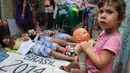 Seorang anak berpose berlatar belakang anggota LSM Rio de Paz yang sedang melakukan aksi protes terhadap sistem perawatan kesehatan masyarakat jelang pelaksanaan Piala Dunia 2014, Brasil, (10/5/2014). (AFP PHOTO/Tasso Marcelo) 