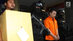 Tersangka pembunuh satu keluarga di Bekasi Haris Simamora (dua kanan) mendapat pengawalan polisi bersenjata di Polda Metro Jaya, Jakarta, Kamis (21/2). Selain Haris, polisi juga akan menyerahkan barang bukti dalam kasus ini. (Merdeka.com/Imam Buhori)