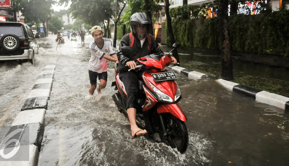 Warga membantu mendorong motor saat melewati banjir di kawasan Kemang, Jakarta, Jumat (11/11). (Liputan6.com/Yoppy Renato)