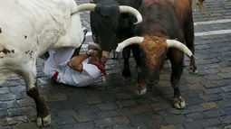 Salah satu peserta terlihat terjatuh dan terinjak oleh komplotan banteng yang berlari saat Festival San Fermin Pamplona, Spanyol, Selasa (7/7/2015). (Reuters/Susana Vera)