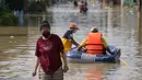 Seorang wanita mengarungi jalan yang banjir di Bekasi, Jawa Barat, Kamis (17/2/2022). Hujan deras yang dikombinasikan dengan perencanaan pembuangan limbah kota yang buruk sering menyebabkan banjir besar. (AP Photo/Achmad Ibrahim)