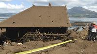 Petugas kepolisian memeriksa rumah yang tertutup lumpur yang rusak akibat longsor akibat gempa di Bangli, Bali, Sabtu (16/10/2021). Beberapa orang tewas dan lainnya luka-luka saat gempa berkekuatan sedang dan gempa susulan menghantam pulau itu Sabtu dini hari. (AP Photo/Dewa Raka)