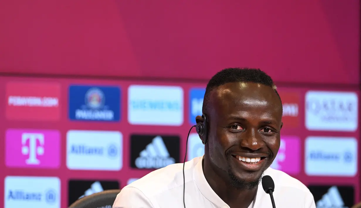 Penyerang baru Bayern Munchen, Sadio Mane tersenyum selama konferensi pers setelah ia menandatangani kontrak tiga tahun di Munich, Jerman selatan (22/6/2022). Bayern dilaporkan telah membayar biaya yang bisa naik menjadi 41 juta euro (USD 43 juta) untuk Mane. (AFP/CHRISTOF STACHE)