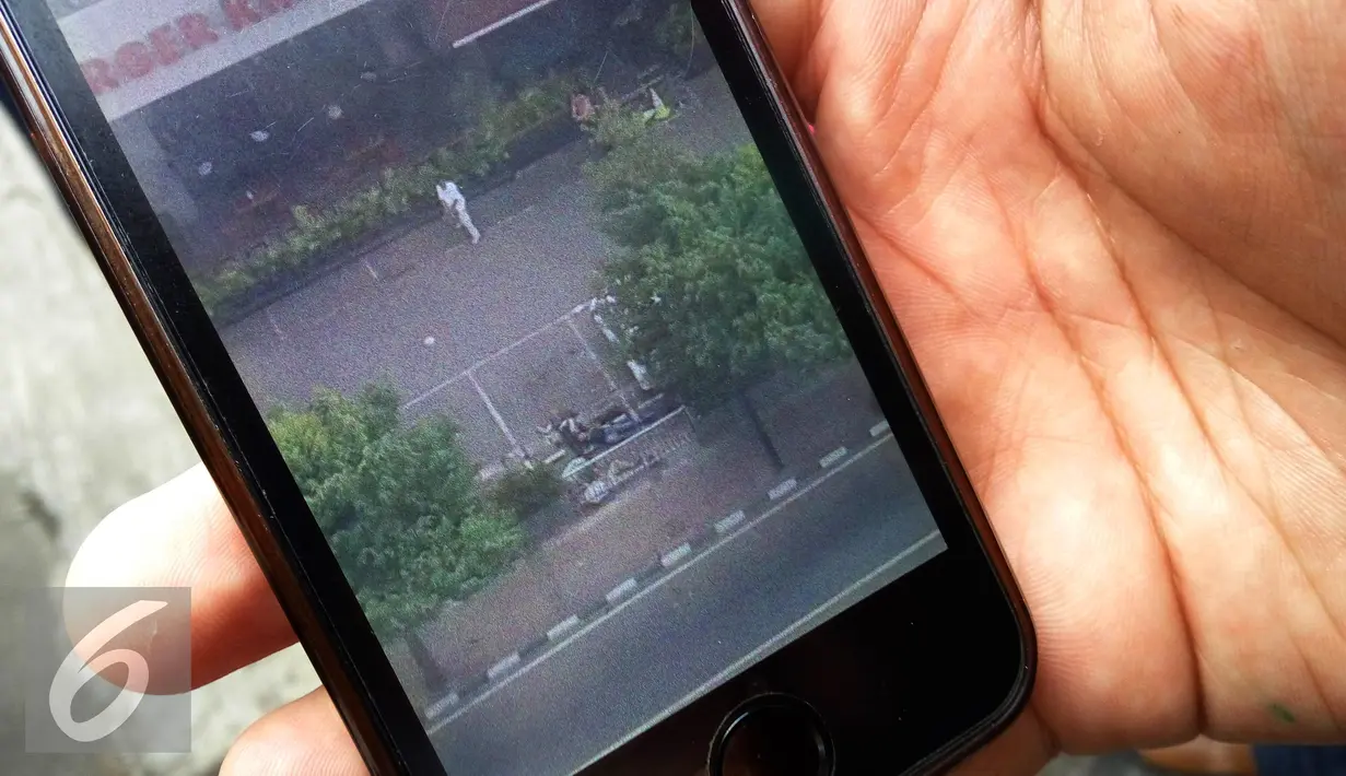 Seorang warga menunjukan gambar pasca ledakan di pos polisi perempatan Sarinah, Jakarta, Kamis (14/1/2016). Setelah ledakan terjadi adu tembak antara polisi dan pelaku di gedung DJakarta Theater. (Liputan6.com/Angga Yuniar)