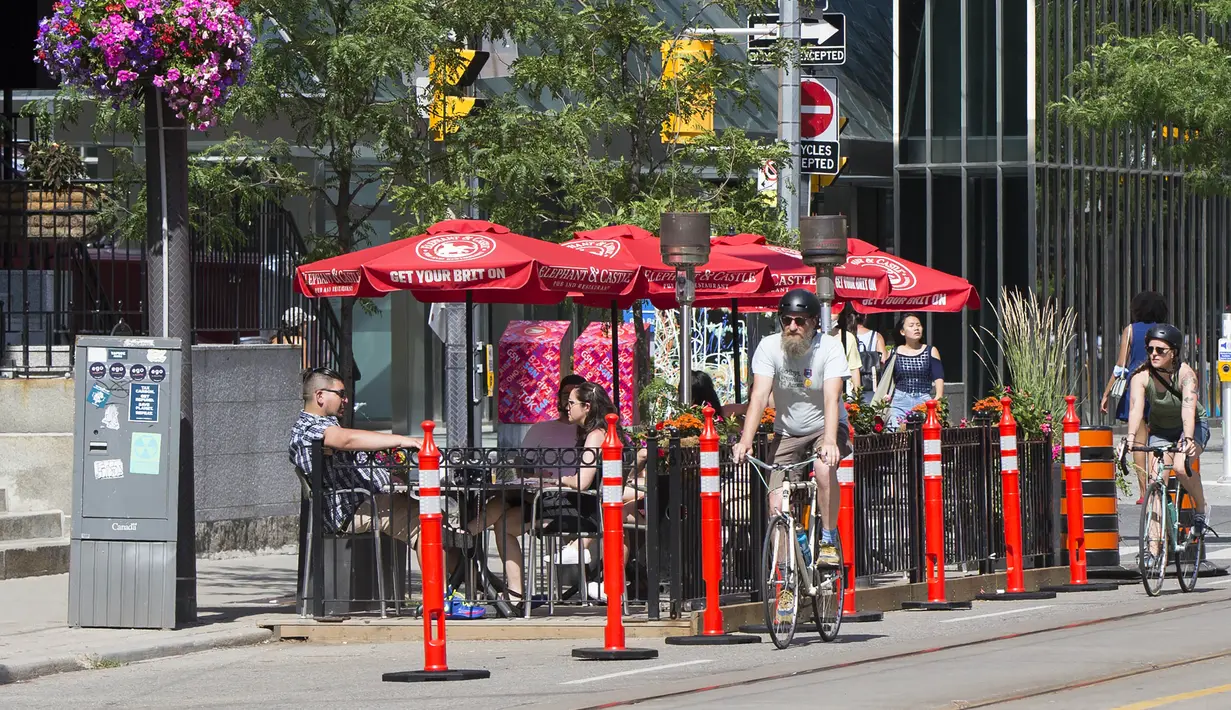 Pengendara sepeda melewati area makan terbuka sebuah restoran di Toronto, Kanada, 18 Juli 2020. Kota Toronto meluncurkan program CafeTO yang memungkinkan restoran dan bar memperluas area makan terbuka mereka guna melayani lebih banyak pelanggan dengan aman selama pandemi COVID-19. (Xinhua/Zou Zheng)