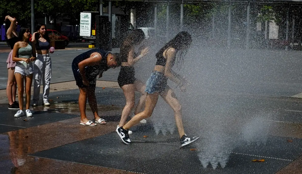 Orang-orang mendinginkan diri di air mancur di Pamplona, Spanyol, 15 Juni 2022. Layanan cuaca Spanyol mengatakan massa udara panas dari Afrika Utara memicu gelombang panas besar pertama di negara itu tahun ini dengan suhu diperkirakan akan meningkat menjadi 43 derajat Celcius (109 derajat Fahrenheit) di area tertentu. (AP Photo/Alvaro Barrientos)