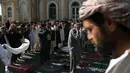 Seorang pria melitas di dekat jamaah yang sedang melakukan salat Idul Fitri di luar masjid Shah-e-Dushamshera di Kabul, Afghanistan (25/6). (AP Photo / Rahmat Gul)