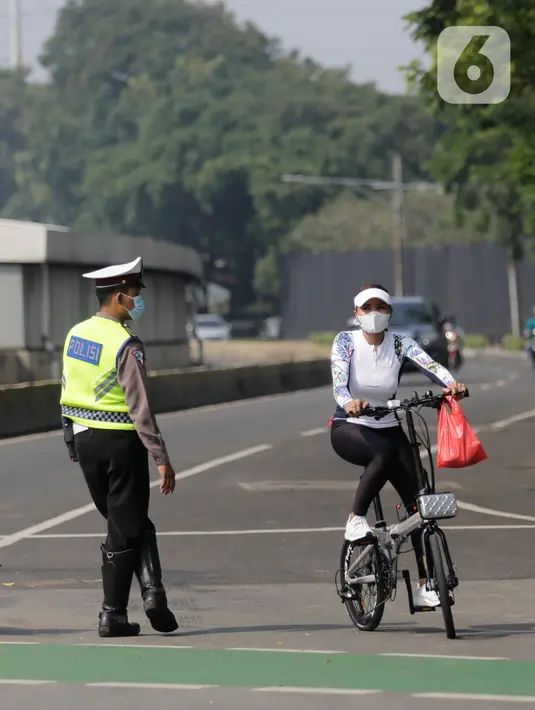 Petugas gabungan melakukan pengalihan jalur pesepeda di kawasan Sudirman-Thamrin, Jakarta, Minggu (5/9/2021). Pemberlakuan jalur ganjil genap pada masa PPKM membuat pengguna sepeda dilarang melintasi kawasan ganjil-genap pagi ini. (Liputan6.com/Angga Yuniar)