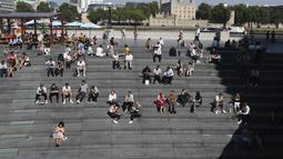 Orang-orang makan siang sambil duduk di bawah sinar matahari di Scoop dengan latar belakang Menara London saat suhu mendekati 30 derajat celsius di London, Selasa (7/9/2021).  (AP Photo/Tony Hicks)