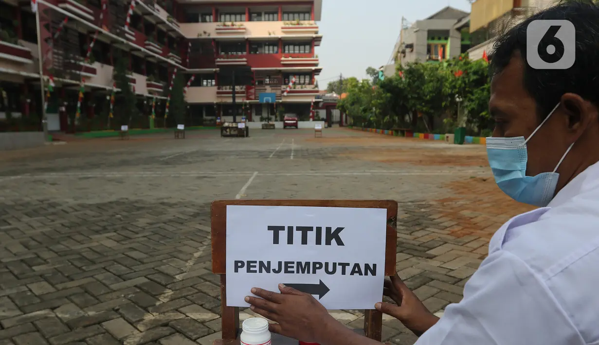 Petugas memasang kertas pemberitahuan “Titik Penjemputan” di SDN 05 Kalisari, Jakarta, Senin (30/8/2021). Pemprov DKI menggelar pembelajaran tatap muka di tengah  covid-19 mulai 30 Agustus 2021 secara terbatas dengan kapasitas 50 persen pada setiap satuan pendidikan. (Liputan6.com/Herman Zakharia)
