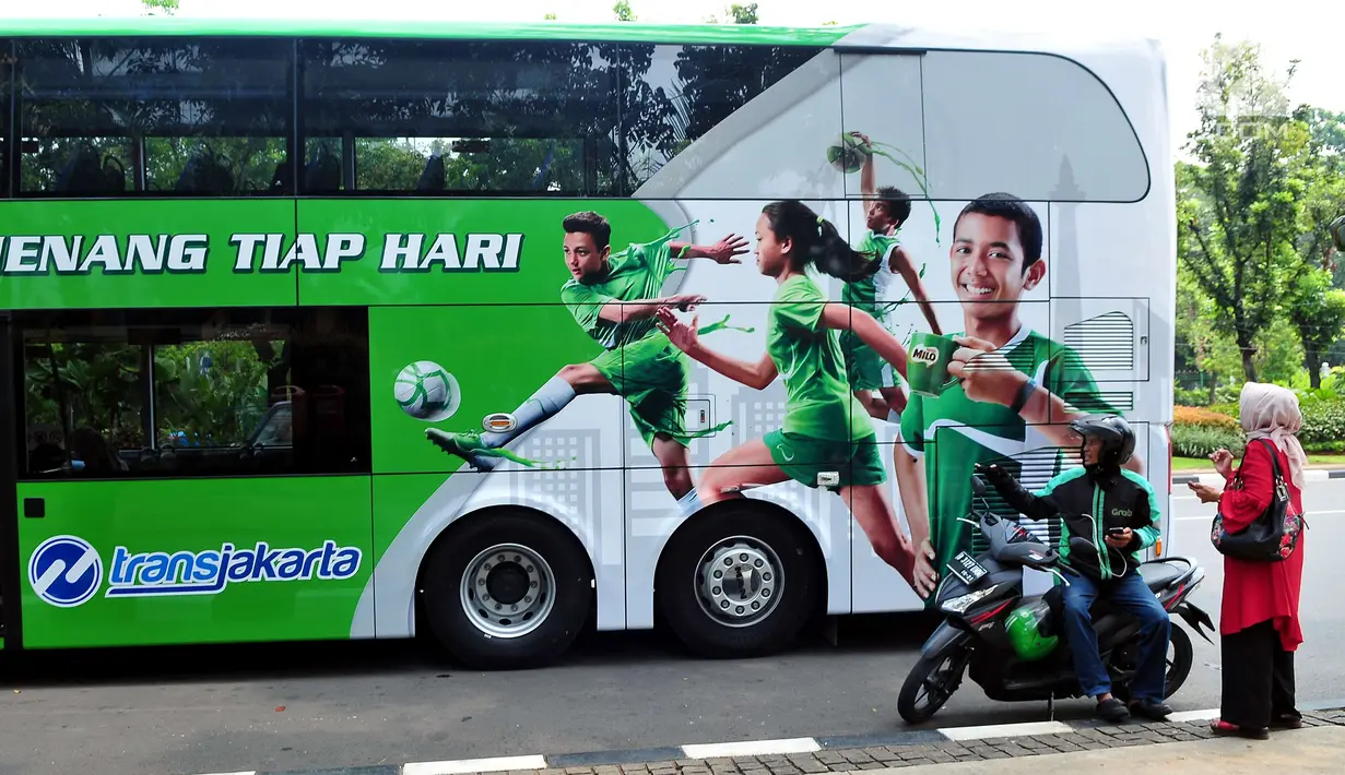 Bus tingkat wisata melintas dekat pengemudi ojek online di depan Balai Kota DKI Jakarta, Rabu (11/10). Pemprov DKI kembali menerima hibah satu unit bus tingkat pariwisata Transjakarta berkapasitas 76 penumpang dari PT Nestle. (Liputan6.com/Helmi Afandi)