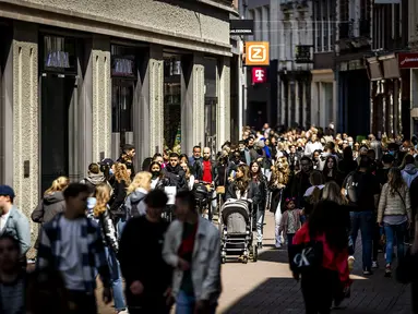 Pelanggan berjalan di Kalverstraat shopping street saat toko-toko diizinkan menerima pelanggan tanpa membuat janji di Amsterdam, Rabu (28/4/2021). Belanda melonggarkan pembatasan ketat terkait Covid-19, mengakhiri jam malam dan mengizinkan kafe untuk buka di luar ruangan. (REMKO DE WAAL/ANP/AFP)