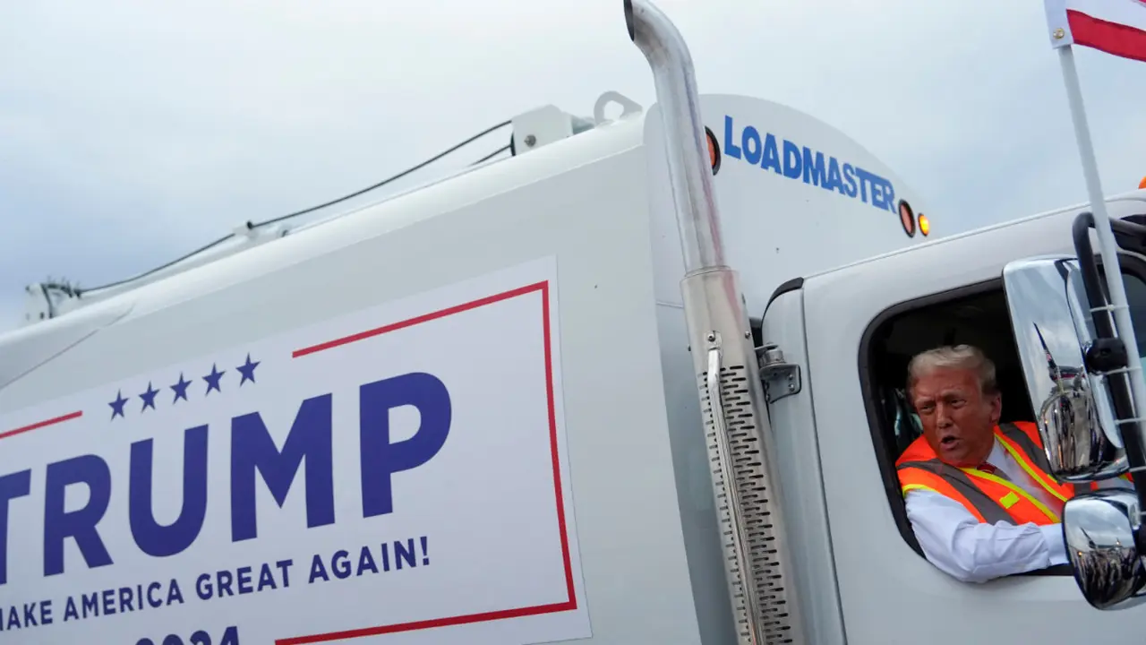 Donald Trump mengendarai truk sampah berwarna putih dengan tulisan "TRUMP, Make America Great Again 2024" (Dok. AP).