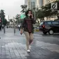 Seorang wanita berjalan mengenakan masker pelindung untuk menghindari polusi udara buruk di Jakarta, Rabu (17/7/2019). Dinkes DKI menyarankan masyarakat untuk menggunakan masker saat beraktivitas untuk mencegah dampak polusi udara pada tubuh. (Liputan6.com/Faizal Fanani)