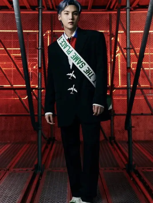 Suga pun menjadi penampil ketiga, suit hitam dengan detail kancing pesawat dan sash.(Louis Vuitton)