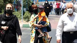 Warga Iran mengenakan masker saat mereka berjalan di sepanjang jalan di ibu kota Teheran, Sabtu (3/7/2021). Presiden Hassan Rouhani mengaku khawatir Iran akan dilanda gelombang kelima pandemi Covid-19 karena kemunculan virus corona varian Delta. (ATTA KENARE/AFP)