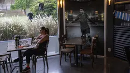 Seorang perempuan makan siang di sebelah foto Lionel Messi di dalam sebuah restoran di Rosario, Argentina, Rabu (14/12/2022). Rosario merupakan kota terbesar di Argentina yang terletak di Provinsi Santa Fe. (AP Photo/Rodrigo Abd)