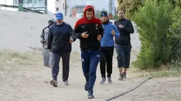 Para pria melakukan jogging sebelum bermain sepak bola di lapangan tanah sebelum buka puasa selama bulan Ramadhan, di ibu kota Libya, Tripoli (24/4/2021). (AFP/Mahmud Turkia)