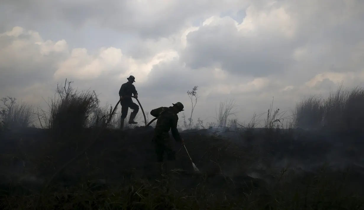 Dua anggota TNI memadamkan api di perkebunan kelapa sawit di Desa Padamaran, Ogan Komering Ilir , Sumatera Selatan, Sabtu (12/9/2015). Kebakaran lahan menyebabkan kabut asap di sejumlah wilayah dan mengganggu jadwal penerbangan. (REUTERS/Beawiharta)